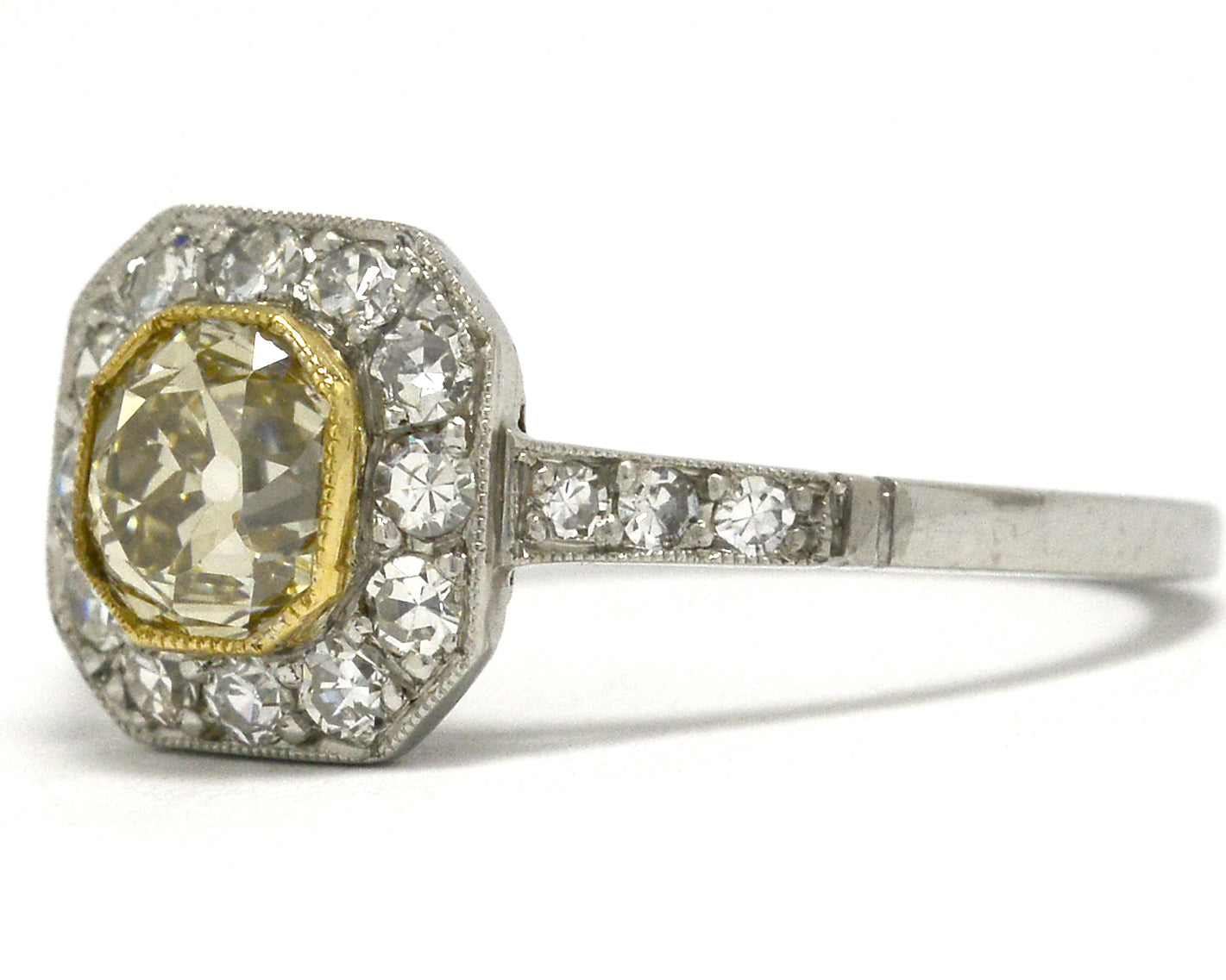 An old mine cushion diamond of light yellow color, set in a platinum ring.
