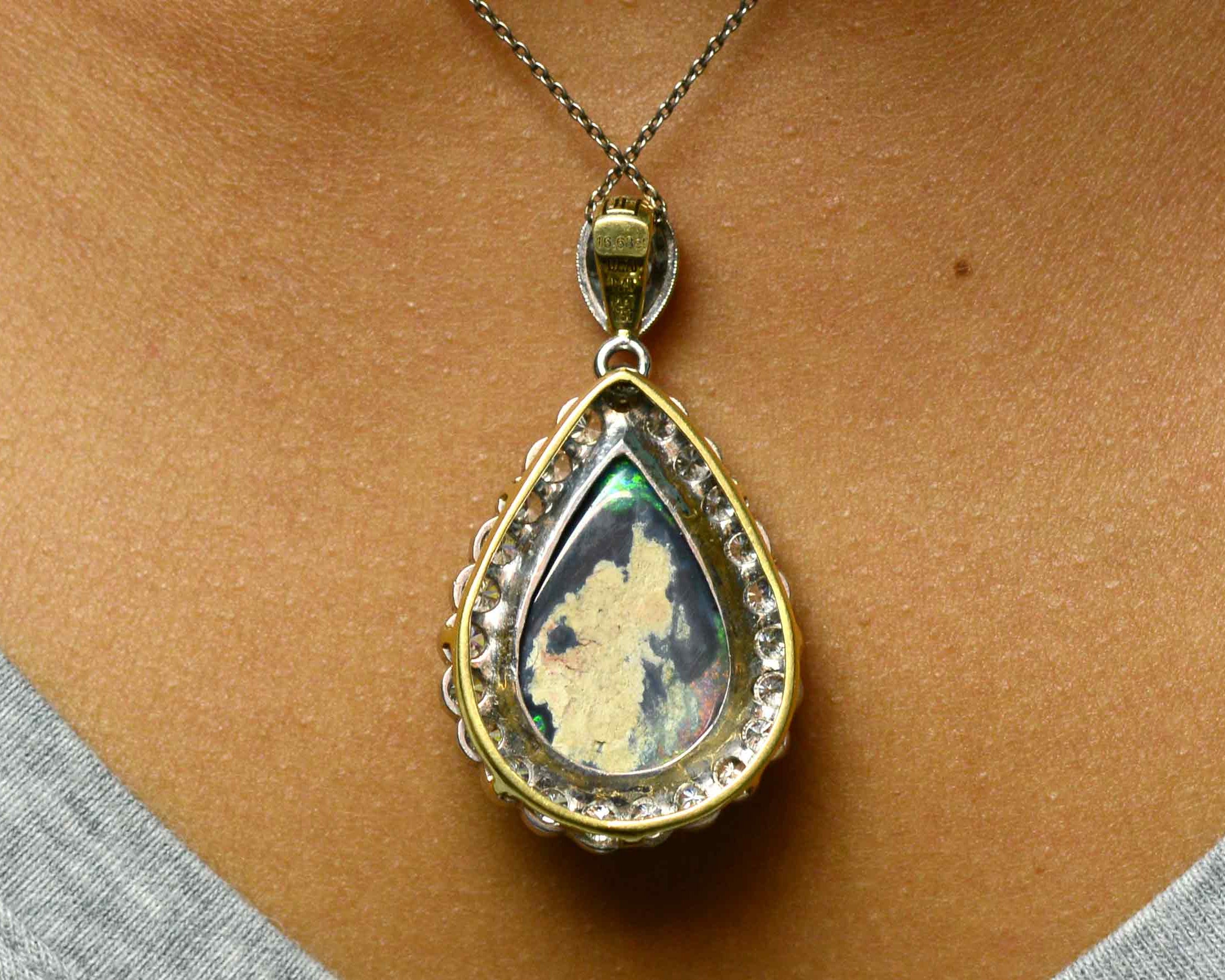 A teardrop shaped black opal platinum pendant with a halo of diamonds.