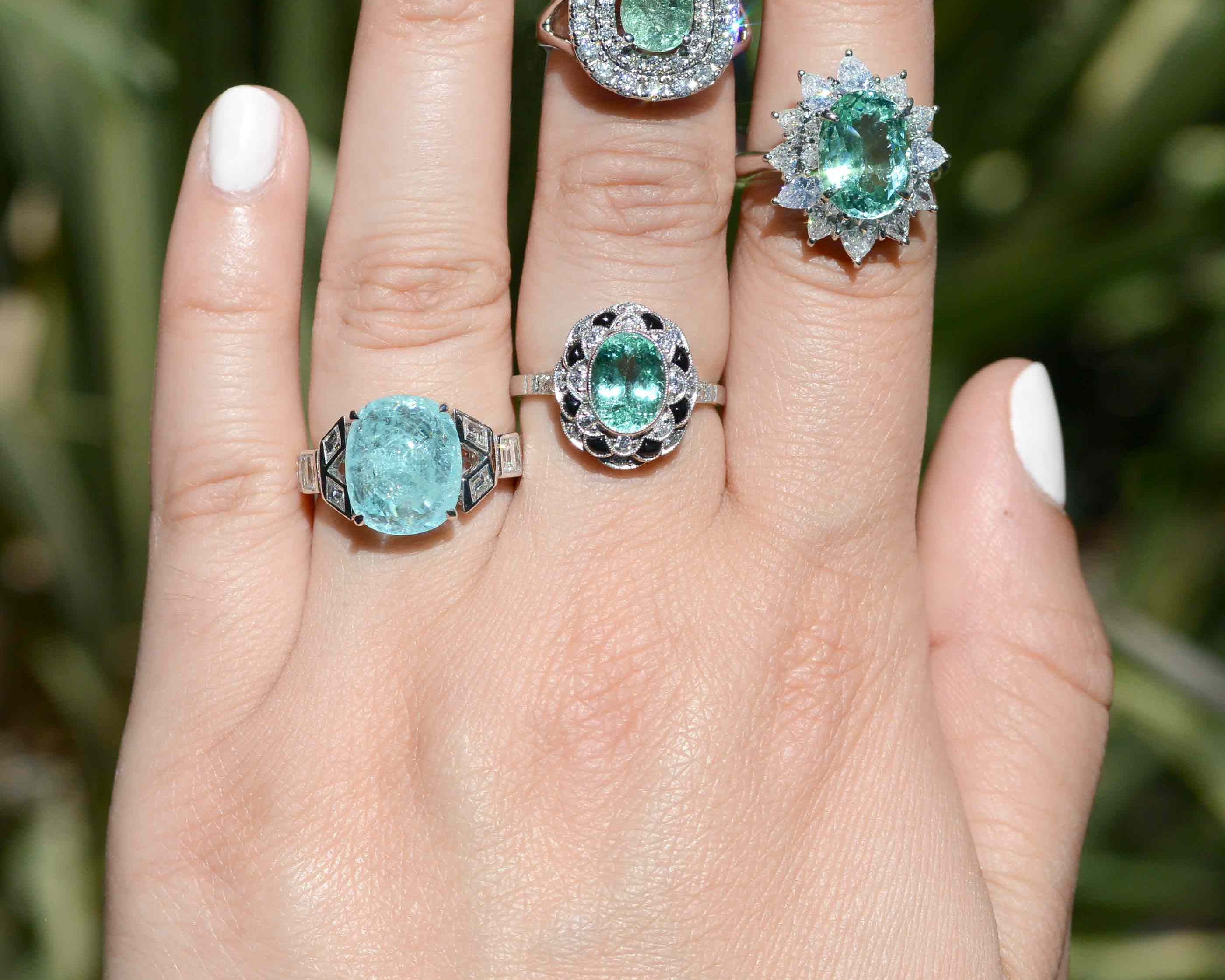 A collection of paraiba tourmaline rings in stock, with the color ranging from aqua to bluish sea-foam green.