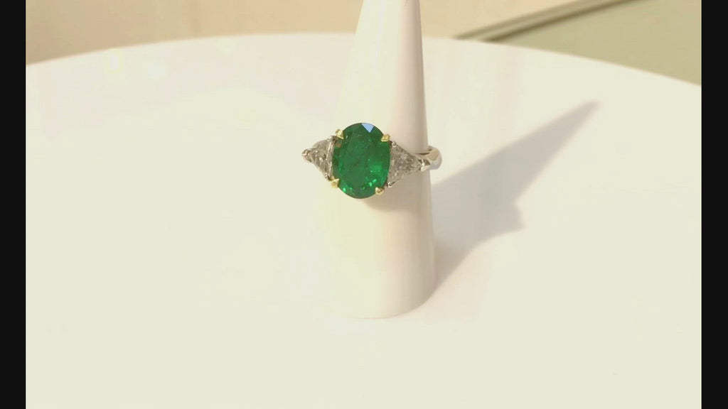 A natural 4 carat emerald is accented by 2 triangle diamonds in this modern engagement ring.