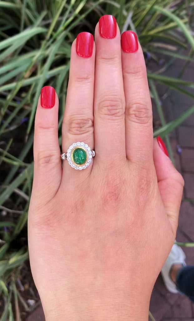 An white gold emerald dome ring with a halo of round diamonds.