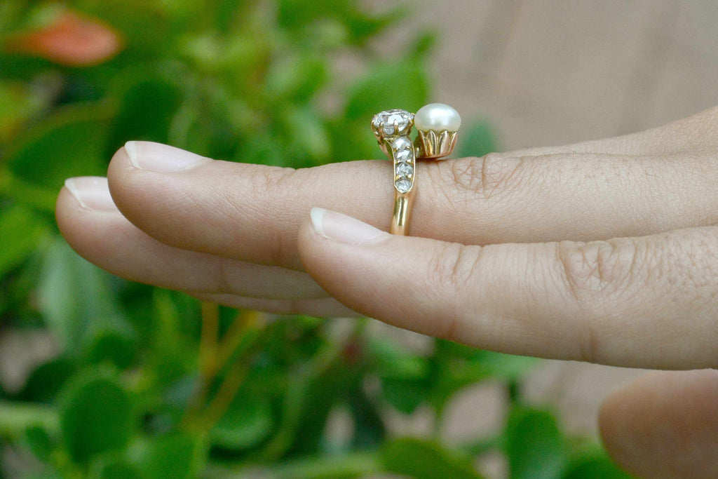 This gold wedding ring features a diamond and pearl in the center.
