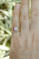 The center gemstone is a glimmering round brilliant cut diamond which is distinctively accented by 10 bezel set rubies.