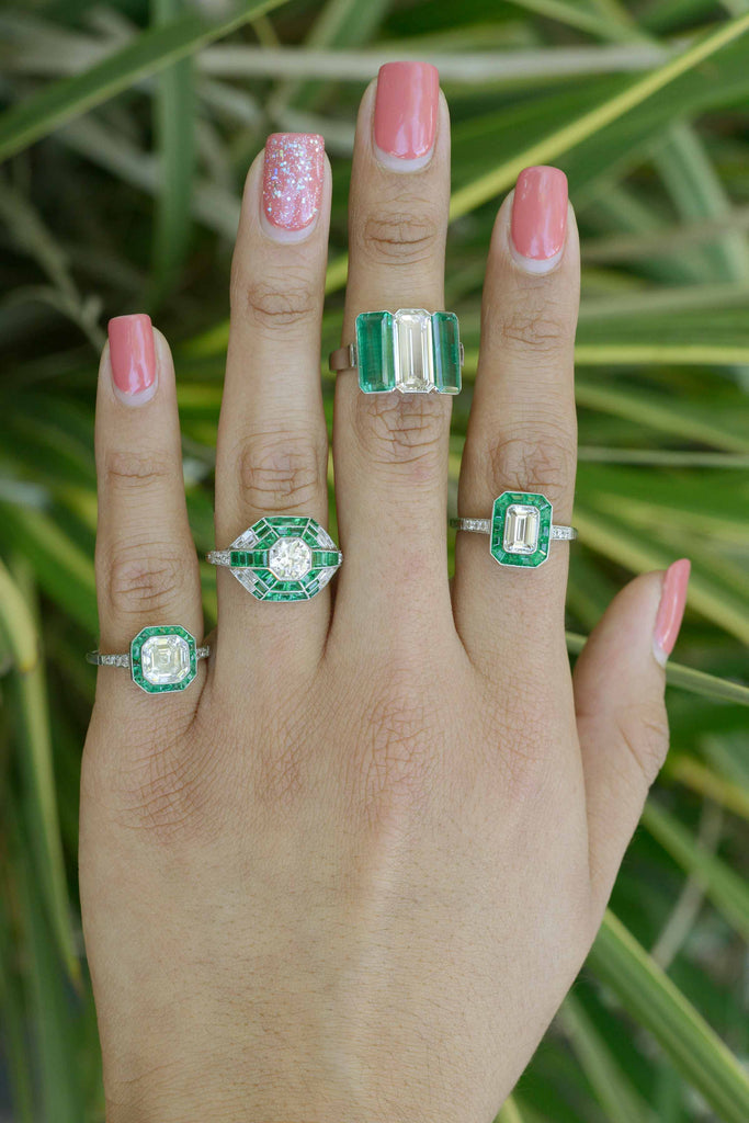 These engagement rings feature a large diamond and several emerald accent gemstones.