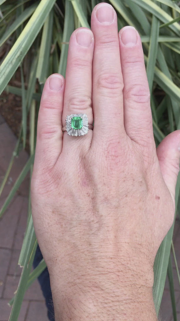 An emerald diamond halo mid century platinum cocktail ring.
