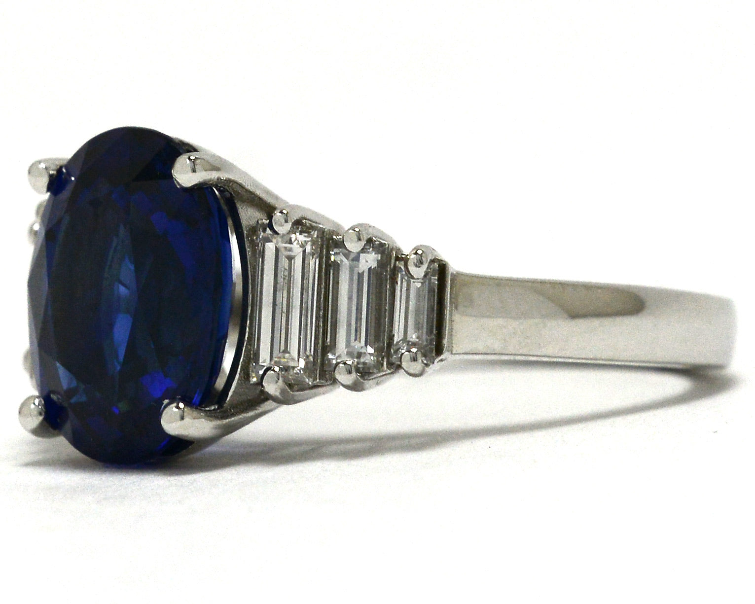 A four carat oval blue sapphire set in a diamond steps, tapered band engagement ring. 
