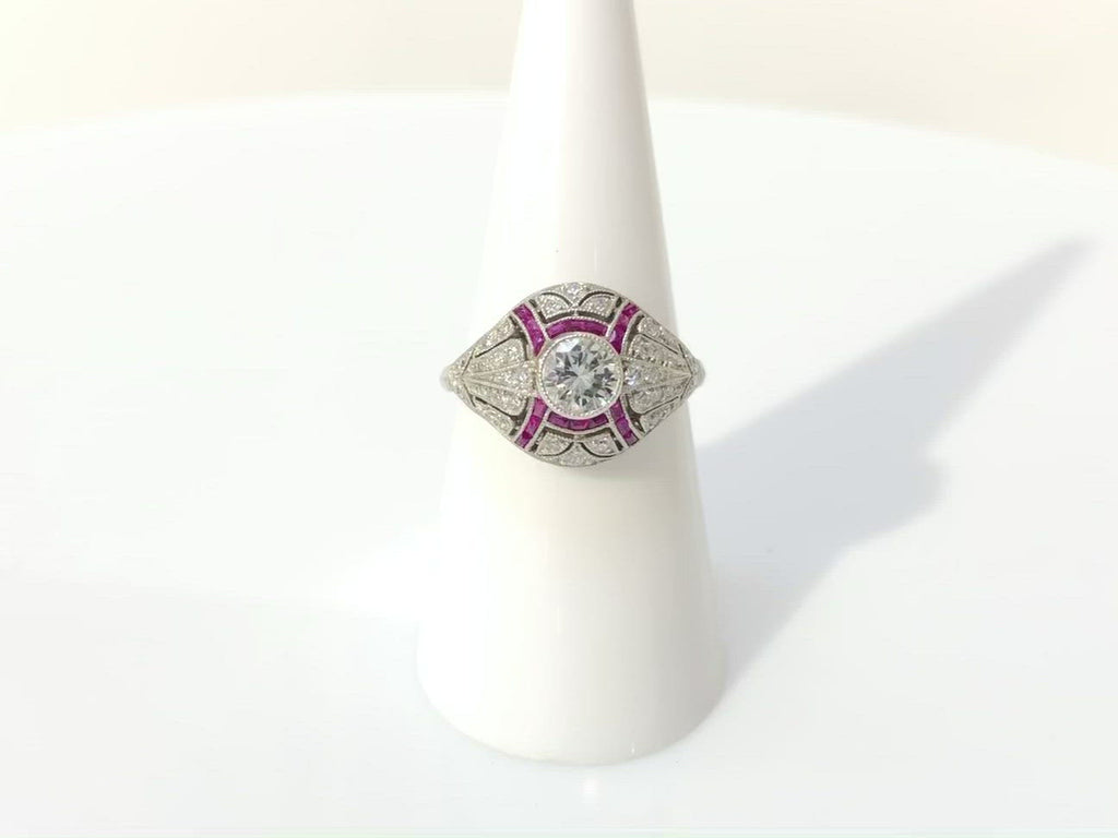 A stunning round brilliant diamond engagement ring accented by French cut rubies.