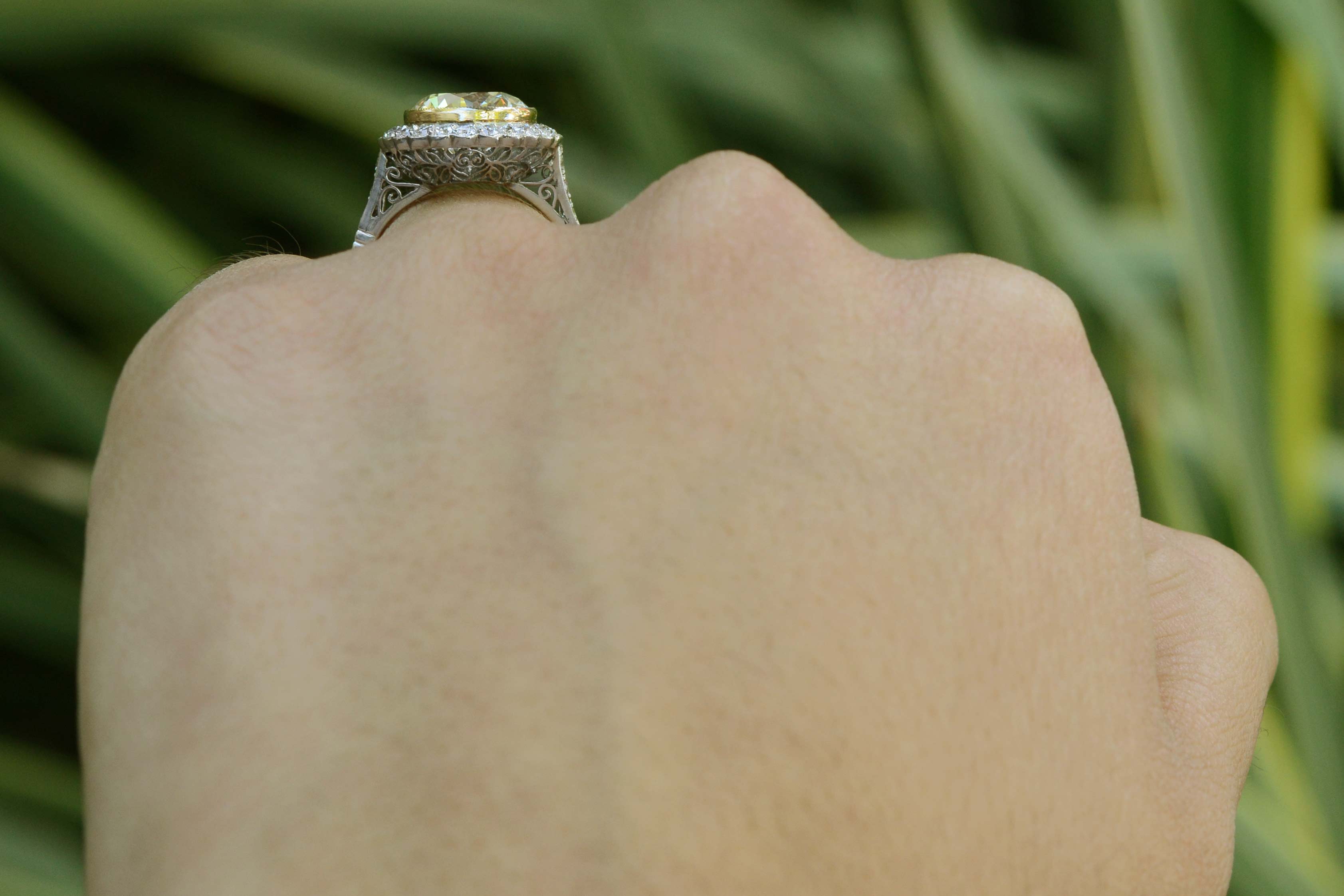 A scalloped halo of diamonds surround the round brilliant yellow diamond in this Art Deco style engagement ring.