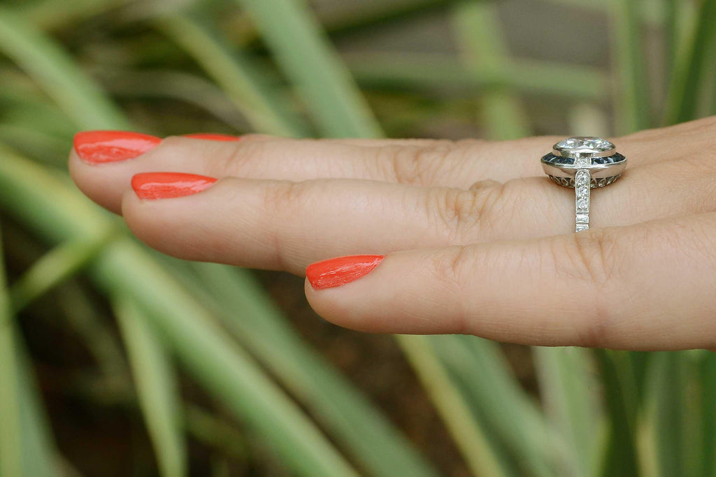Handmade of enduring platinum, securely encased in a bezel surrounded by a luxurious, French cut blue sapphire halo. 