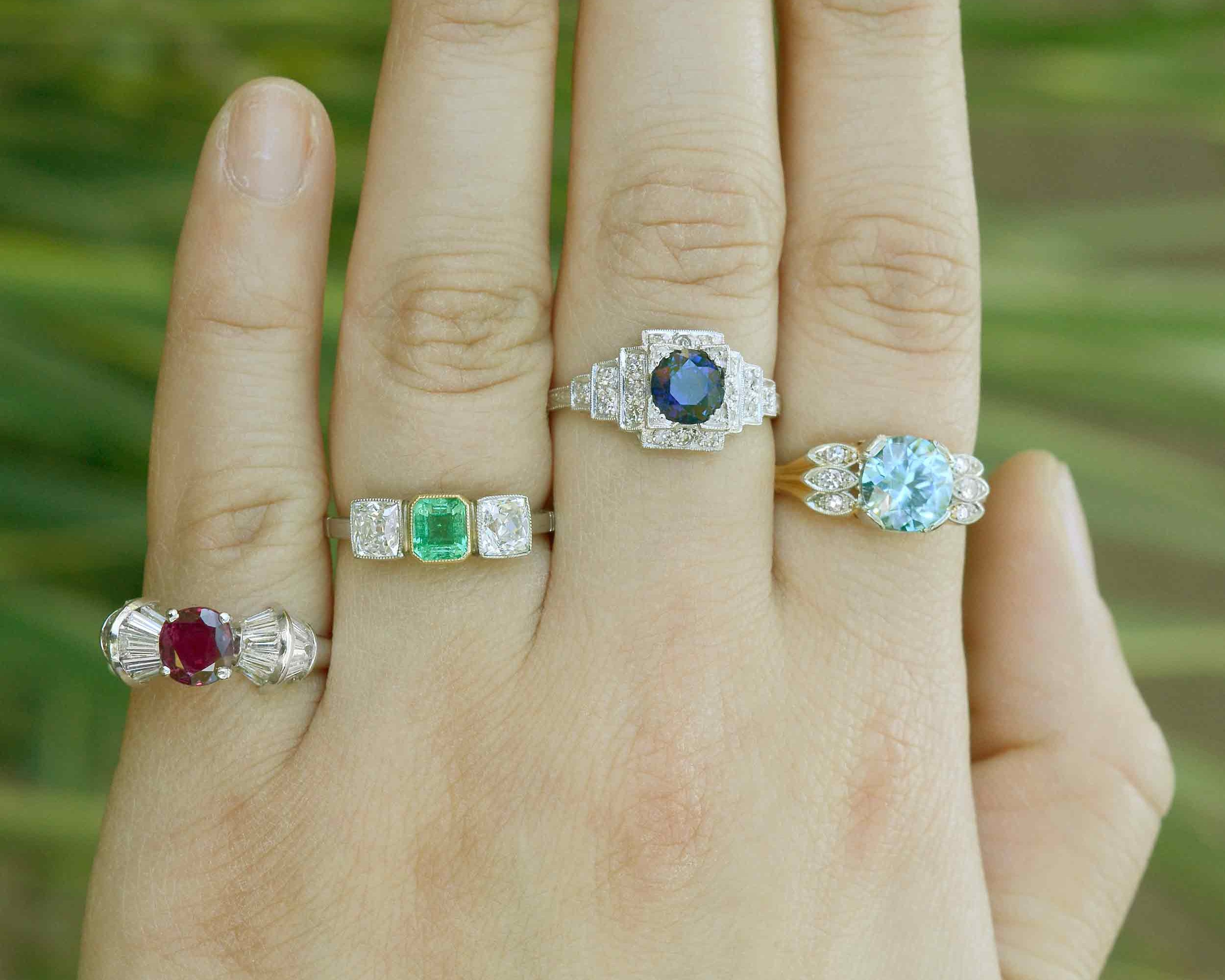 Ruby, emerald and sapphire engagement rings with diamond accents.