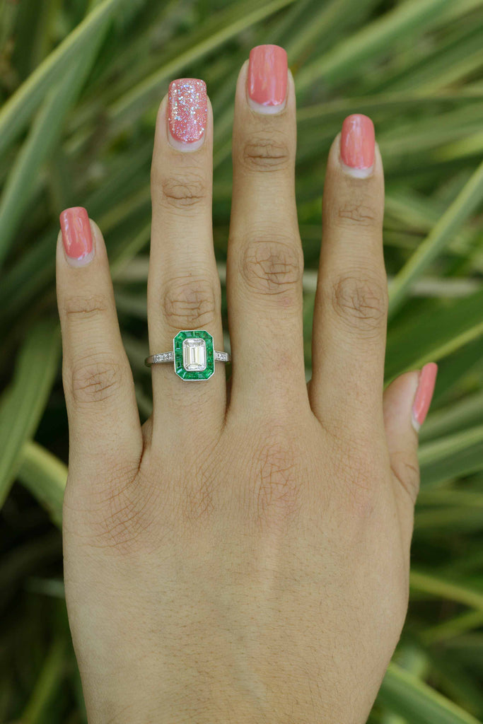 French cut emeralds surround the one carat emerald cut diamond.
