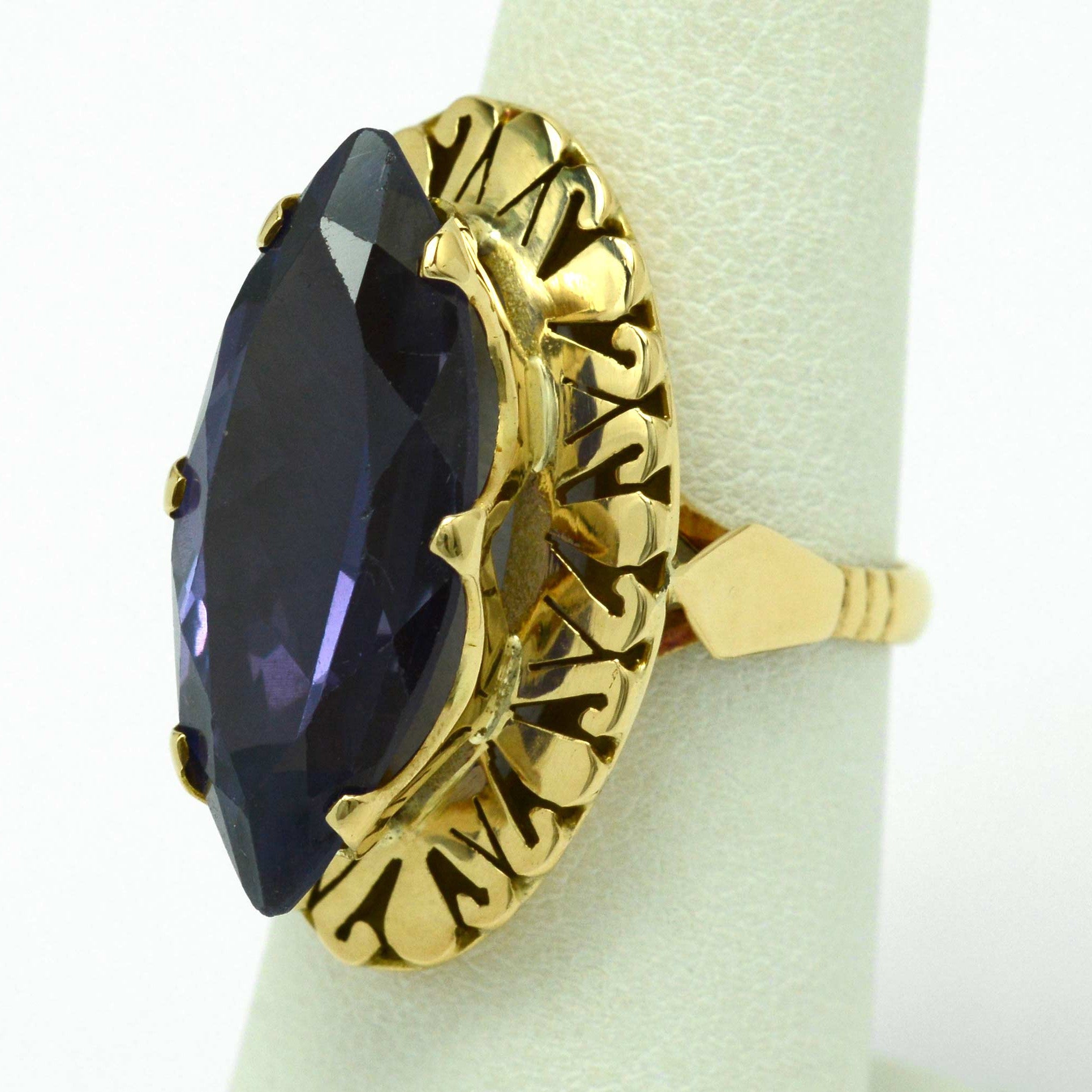 A long navette shaped amethyst ring with filigree gold accents underneath.