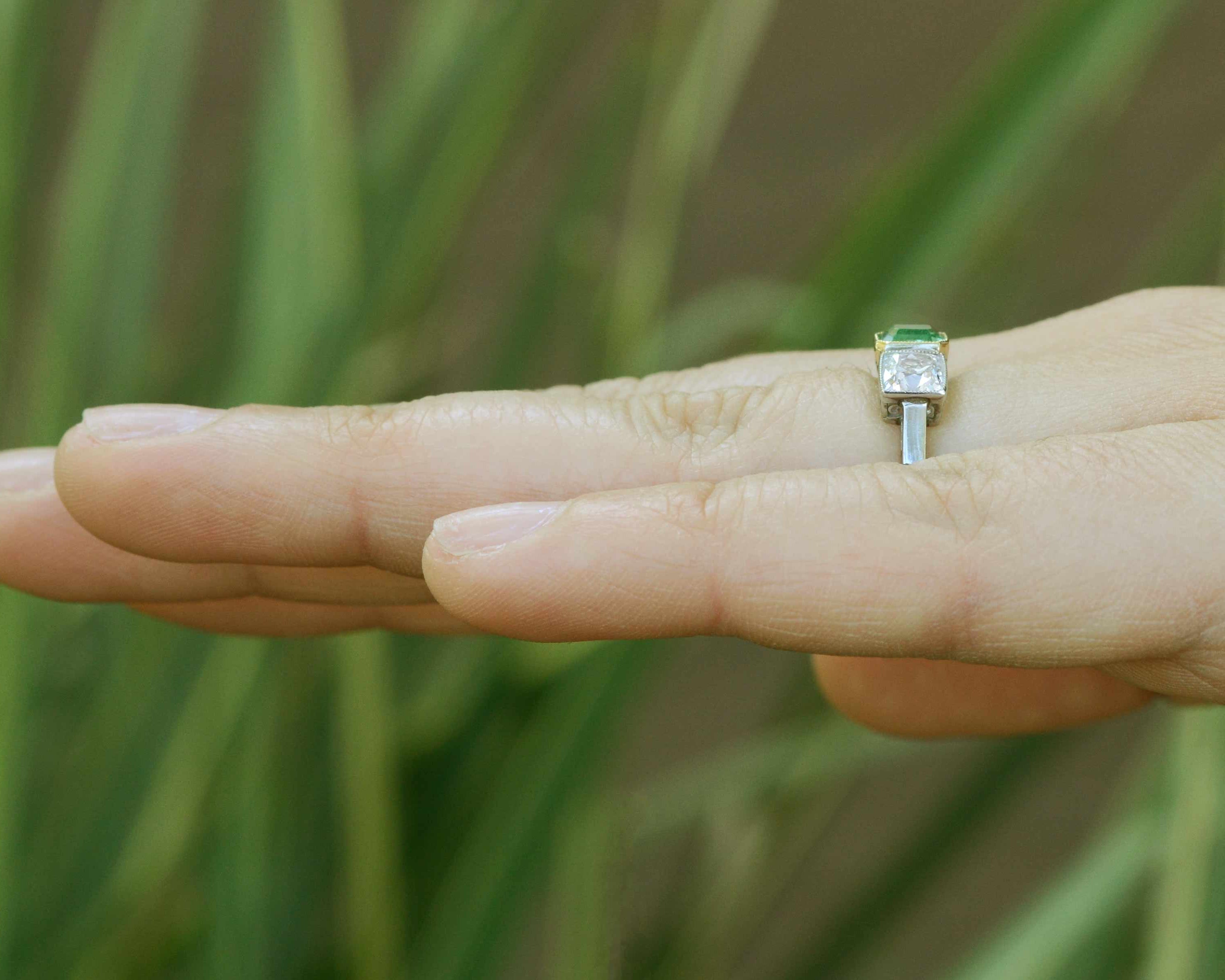 An emerald cut emerald with 2 square cushion diamonds ring.