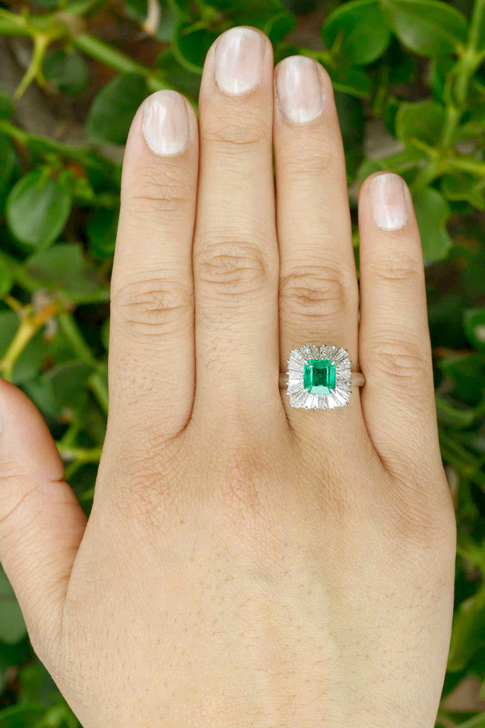 A square shape natural baguette diamonds halo and emerald platinum ballerina ring.