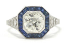 A natural old mine brilliant diamond engagment ring with a halo of blue sapphires.