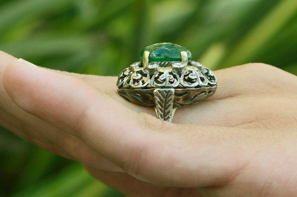 A silver and yellow gold Victorian floral dome ring with a large oval emerald.