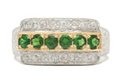 A gold and palladium, 2 tone wedding band with green tsavorite gems.
