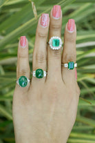 Large emerald platinum engagement rings accented by diamonds.