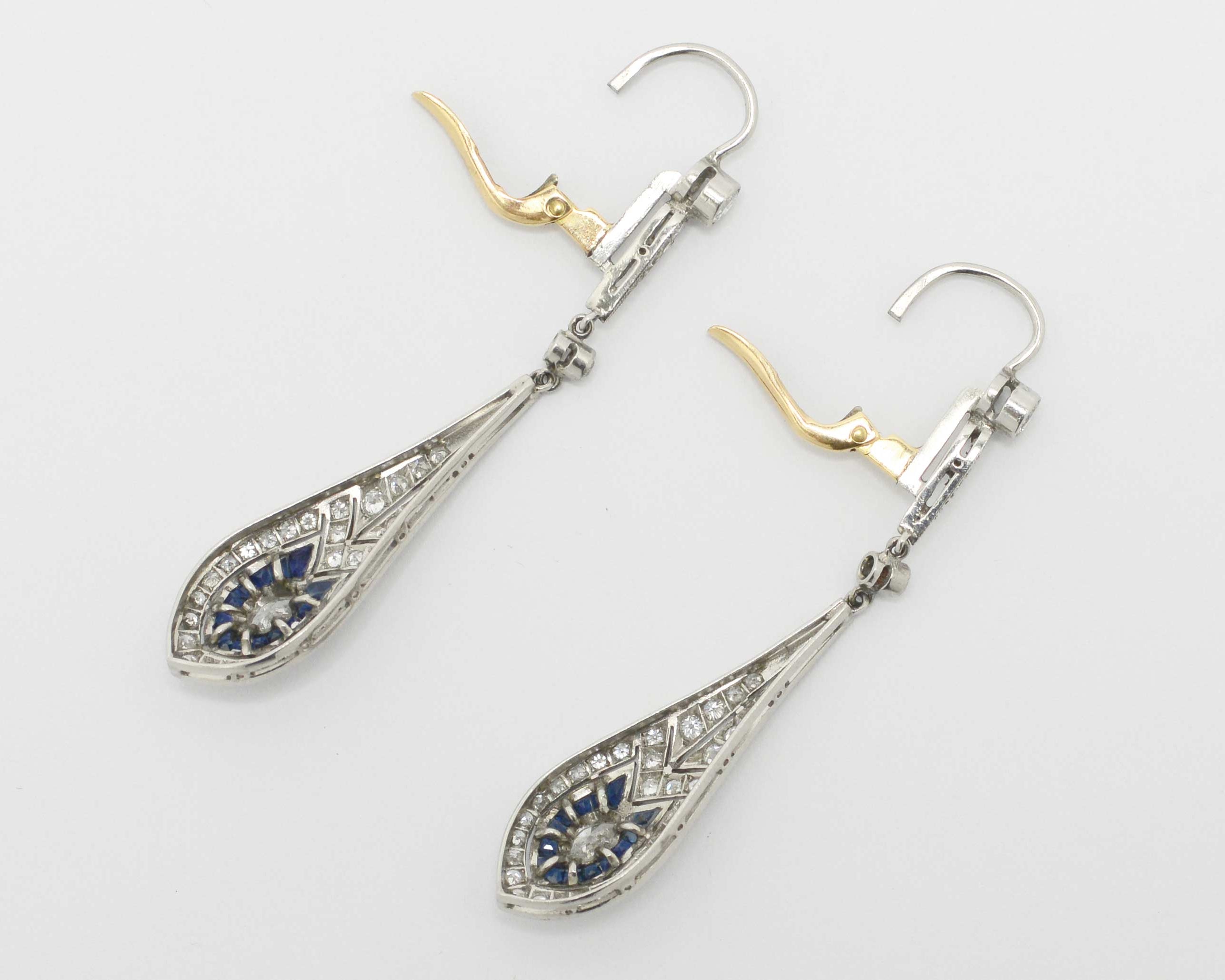 The levers of these diamond and sapphire dangle earrings are made of 18k gold.
