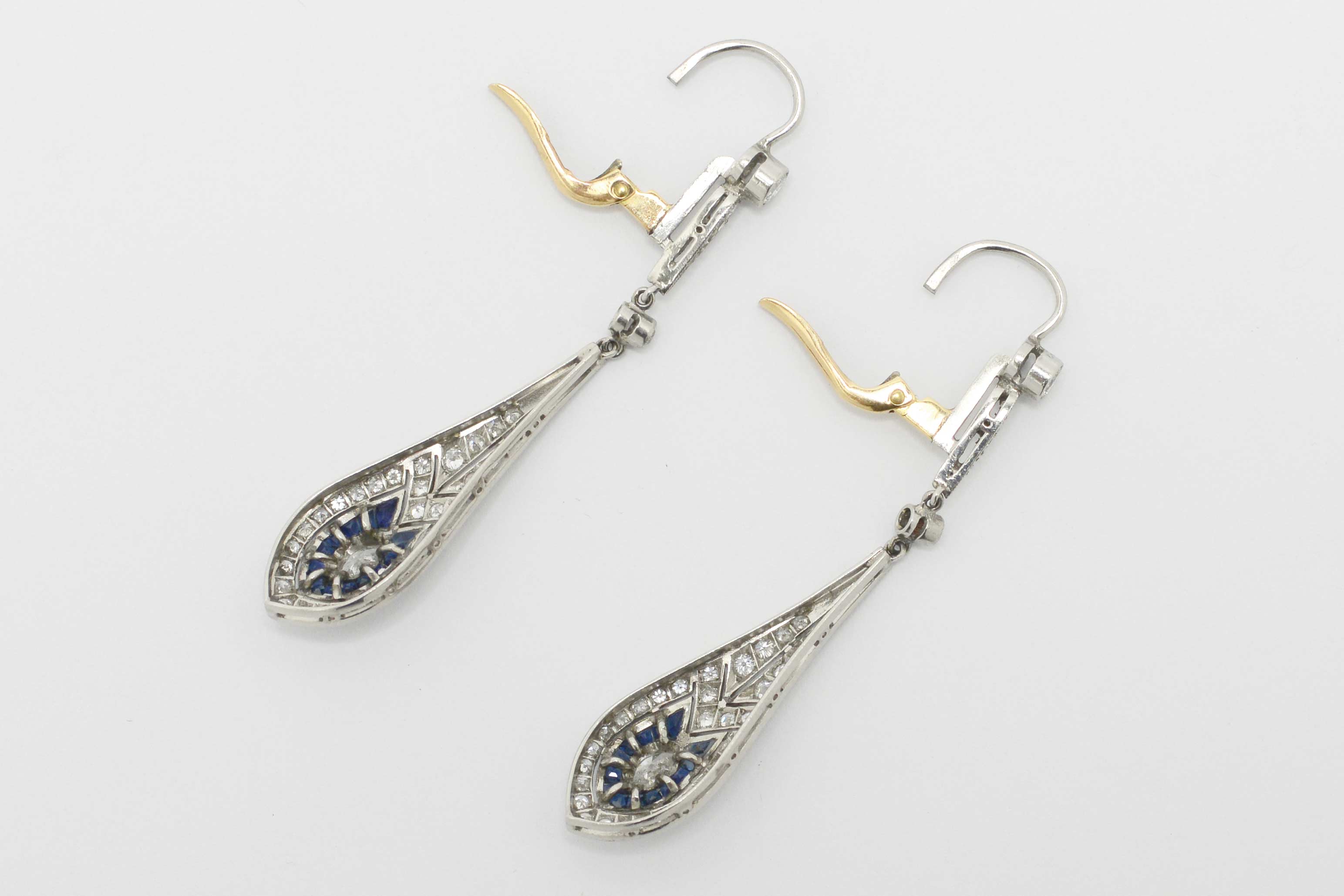The levers of these diamond and sapphire dangle earrings are made of 18k gold.