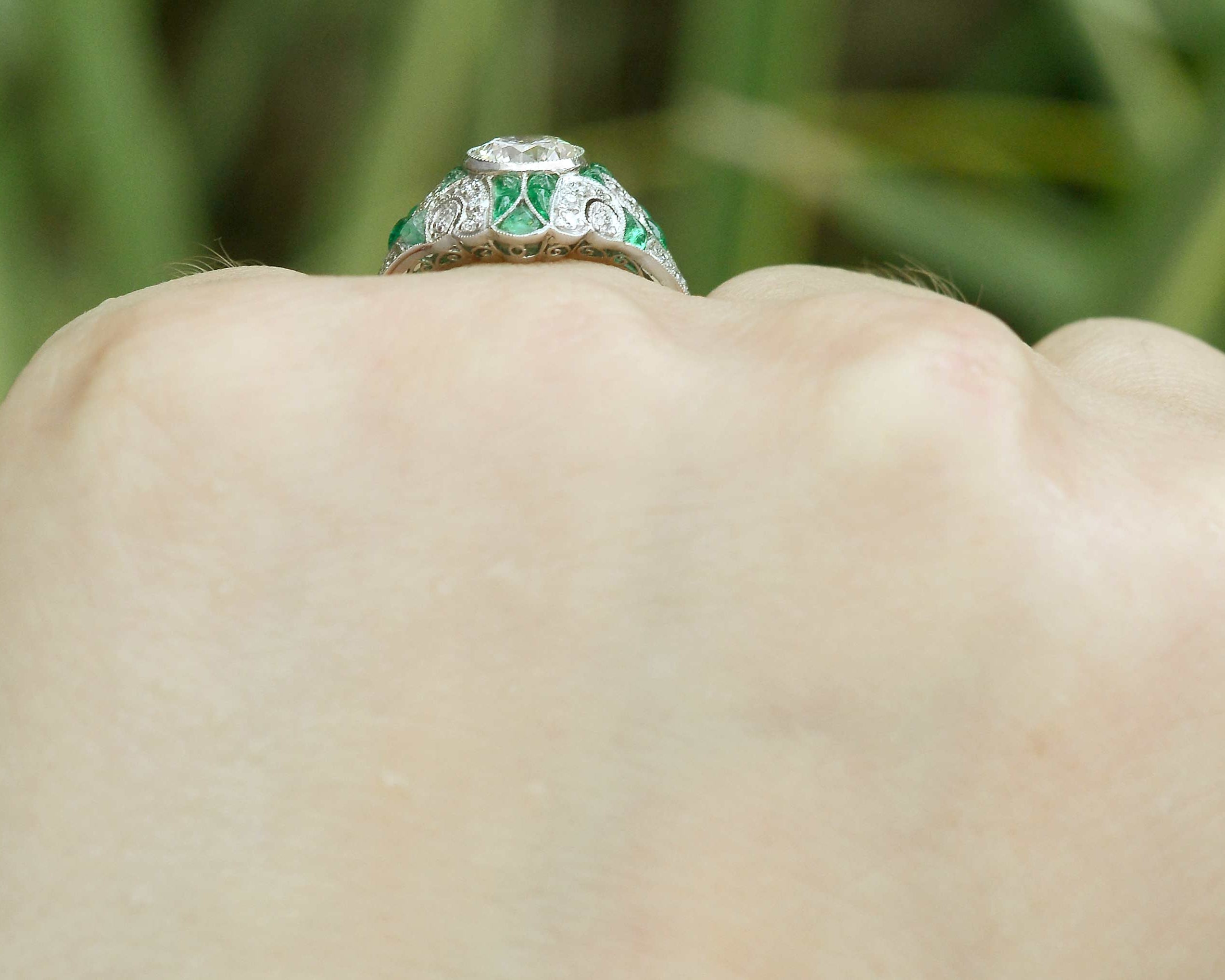 Cabochon cut emeralds line this diamond mosaic engagement ring.
