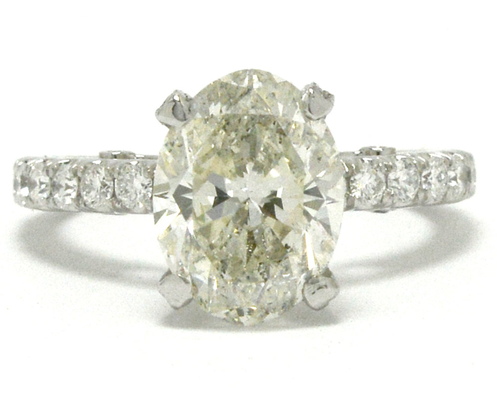 A large oval 3 carat diamond is set in a solitaire engagement ring setting.
