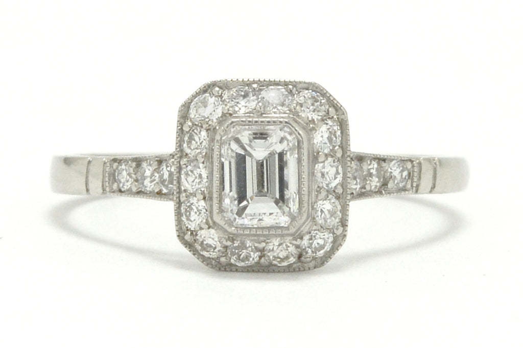 An emerald cut diamond halo Art Deco style engagement ring.