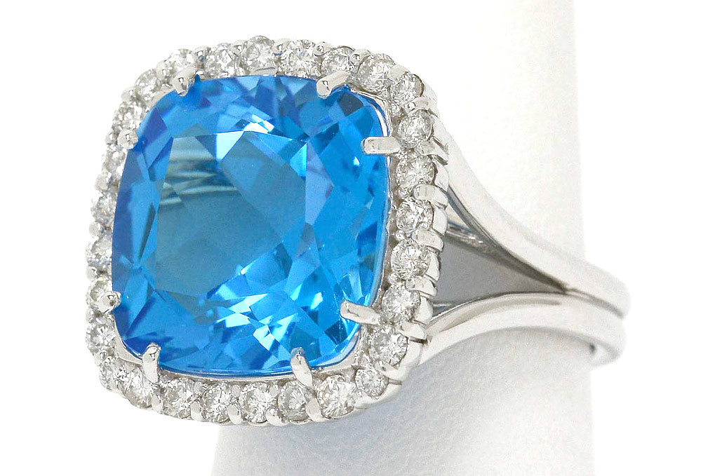 A large, 14 carat blue topaz cocktail ring with a square halo of diamonds.