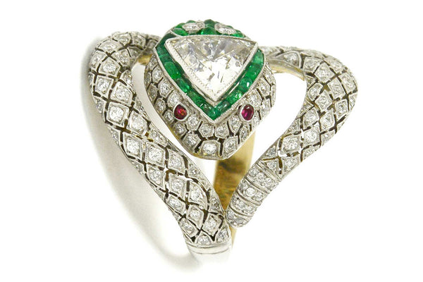 A platinum diamond snake ring with ruby eyes, emeralds surround the trillion cut diamond.