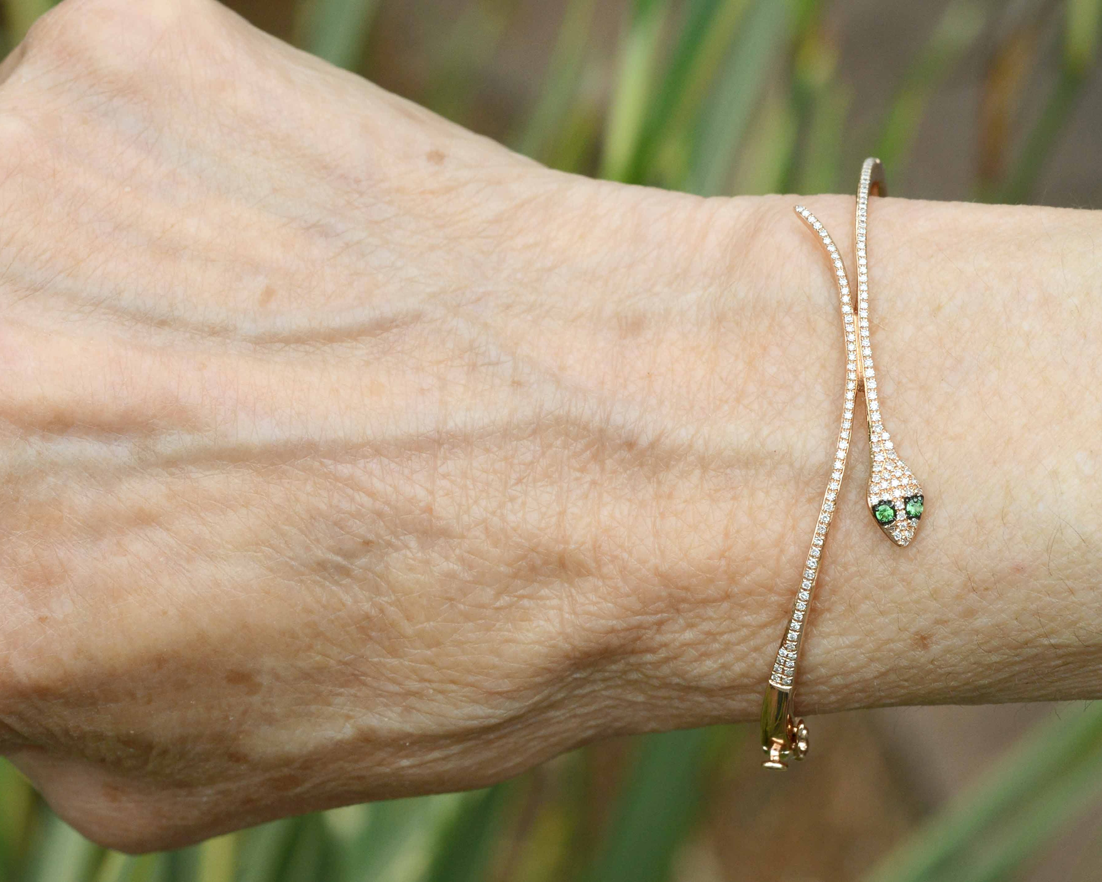 A thin round diamond rose gold snake bracelet with tsavorite eyes.