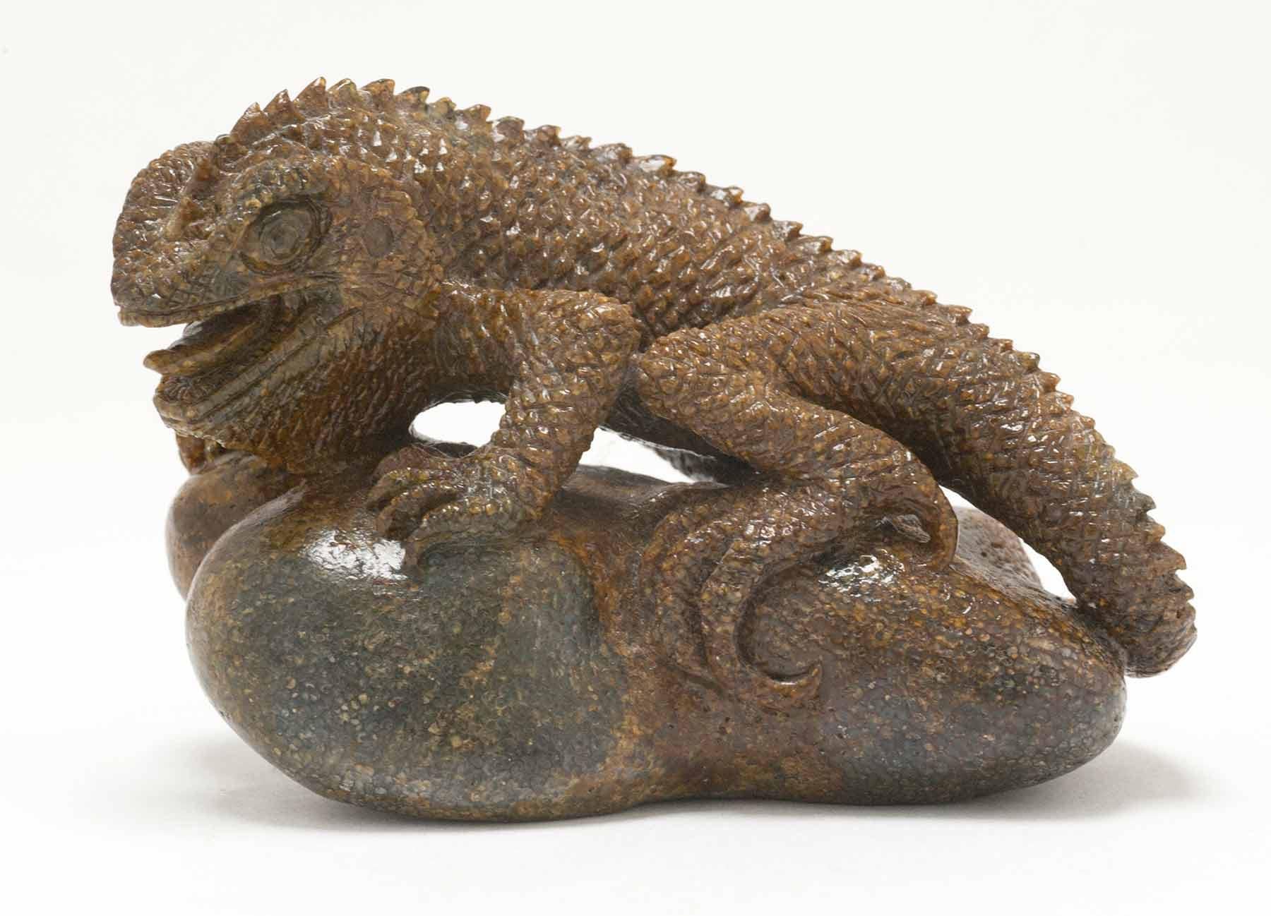 A perched lizard figure, carved out of fossilized whale bone by Ronald Stevens.