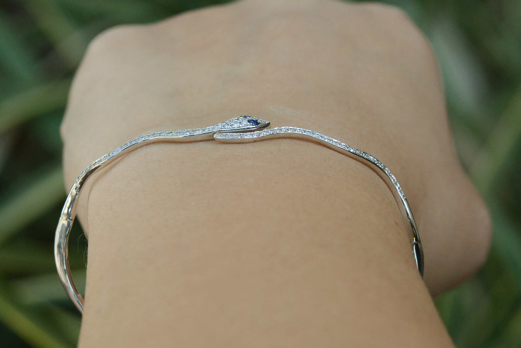 A thin, white gold hinged bangle bracelet.