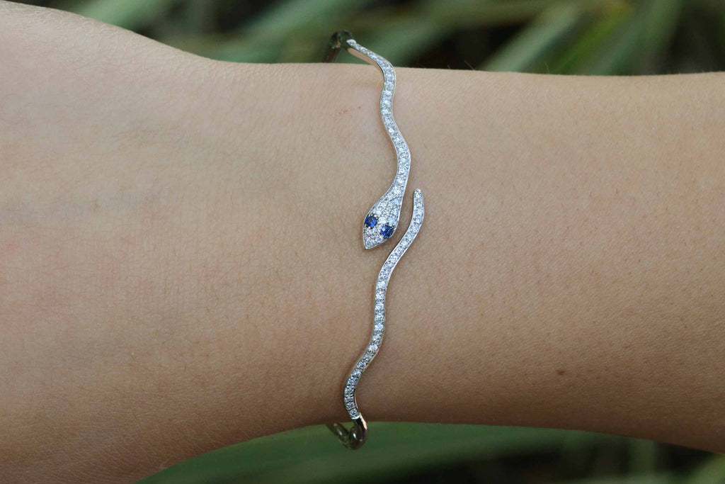 A white gold modern snake bracelet with sapphire eyes.